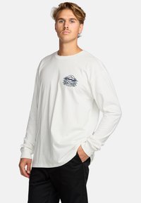 White long-sleeve t-shirt featuring a graphic design in blue and green, made of soft fabric, with a rounded neckline and loose fit.
