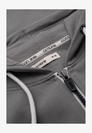 Grauer Zip-Hoodie aus Baumwolle mit Kapuze und Kordelzug, kontrastierendem weißen Reißverschluss und Markenlabel in Größe M. Weicher Stoff.