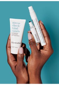 Handcrème tube met een wit en blauw ontwerp, 30 ml; rollerball- en sprayproducten in heldere en witte verpakkingen, tegen een blauwe achtergrond gehouden.