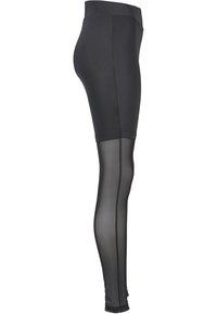Svarta leggings med en solid ogenomskinlig övre sektion och en genomskinlig, transparent nedre sektion. Har en mjuk elastisk midja.