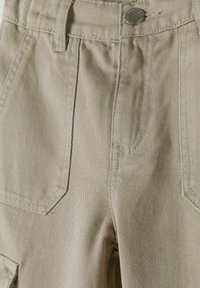 Pantalones cargo beige con una tela texturizada, que cuentan con bolsillos en ángulo, un cierre de botón en la parte delantera y detalles de costura sutiles.