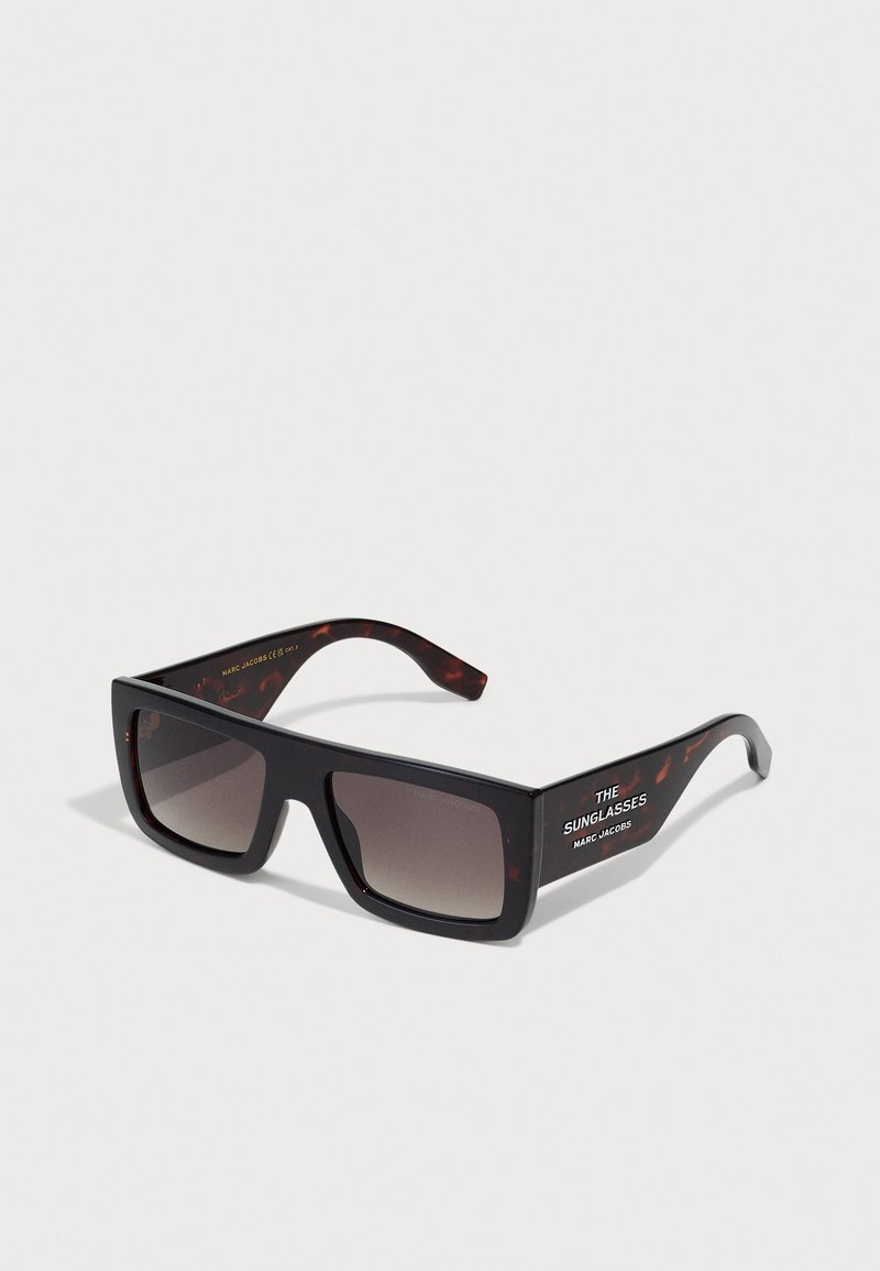 Ochelari de soare supradimensionați, negri, cu lentile întunecate cu gradient. Accente de tartă pe brațele ochelarilor și textul "THE SUNGLASSES MARC JACOBS" pe lateral.