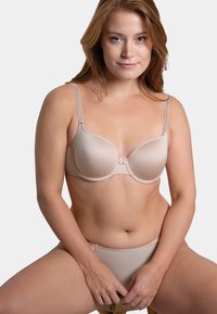 Soutien-gorge à armatures beige clair en tissu lisse, bretelles réglables et délicat nœud au centre. Culotte assortie beige clair.