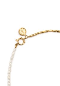 Collana color oro con una fila di perle bianche, dotata di un moschettone circolare e un'etichetta impresso con un logo stilizzato "S".