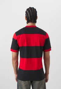 Röd och svart randig t-shirt med korta ärmar och rund hals, tillverkad i lättviktig tyg, med en avslappnad passform och en slät yta.