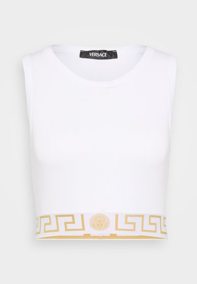 Bela skrajšana majica brez rokavov s krožnim izrezom, ki ima spodnji rob okrašen z zlatim grškim ključi in emblemom Meduze. Narejena iz mehkega materiala.