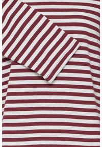 Fehér és sötétvörös csíkos szövet, amelynek egy ujját átlósan a középpont fölé hajtották.