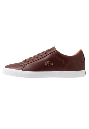 Brun læder lavtop sneaker med snørelukning, hvid sål og guld krokodillelogo på siden.