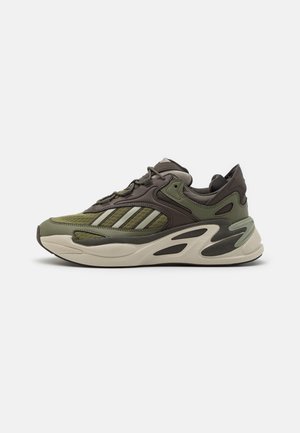 Chaussure de sport verte et marron avec des matériaux en maille et synthétiques, des panneaux texturés, un design à trois bandes et une semelle épaisse et rembourrée.