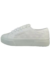 Zapatilla de lona blanca con patrón floral bordado, puntera redonda y suela de goma. Presenta un diseño de cordones y plataforma texturizada.