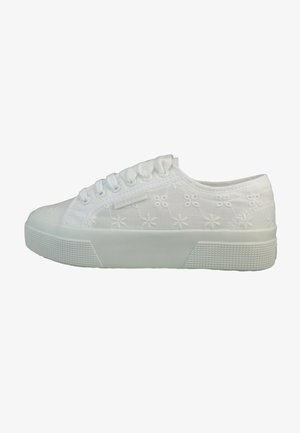 White canvas sneaker with embroidered floral pattern, rounded toe, and rubber sole. Features lace-up design and textured platform.