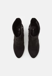 Par de botas de tobillo negras de ante con cremalleras laterales, vistas desde arriba sobre un fondo blanco.