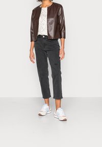 Hnědá bunda z umělé kůže, bílá košile s potiskem, černé džíny a světle modré sportovní tenisky s růžovými akcenty. Moderní střih, ležérní styl.