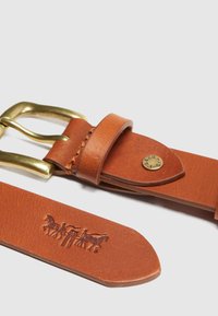 Καφέ δερμάτινη ζώνη με χάλκινη αγκράφα. Διαθέτει ραμμένες λεπτομέρειες και κυκλικό λογότυπο. Με ανάγλυφο σχέδιο με άλογα στο λουρί.