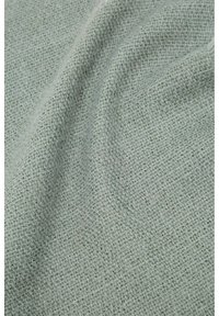 Tissu tissé gris clair avec un motif texturé en forme de grille et de légers plis créant des ombres douces.