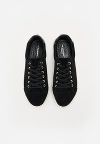 Sneaker in suede nero con occhielli dorati, lacci neri e suola in gomma bianca; punta arrotondata e fodera interna liscia.