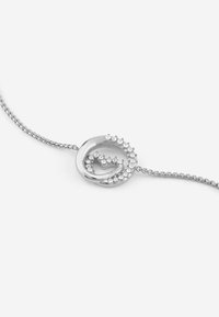 Bracciale in argento con una chiusura circolare decorata con piccole cristalli trasparenti, che creano un design ondulato e una texture liscia.