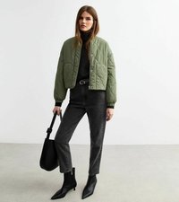 Gequilted groene bomberjack, zwarte coltrui, donkerblauwe hoge taille jeans, zwarte puntige enkelboots en een zwarte handtas.