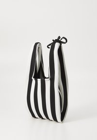 Black and white striped bag featuring a ribbed texture, U-shaped design, and adjustable tie closure at the top.