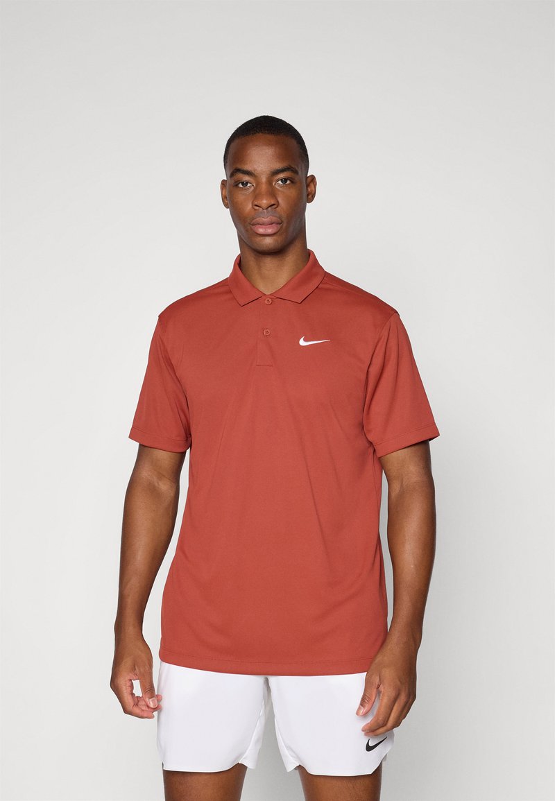 Pánský polo triko s krátkým rukávem Nike v barvě rez, s klasickým límečkem, třemi knoflíky a bílým logem na levé části hrudi. Materiál se zdá být hladký.