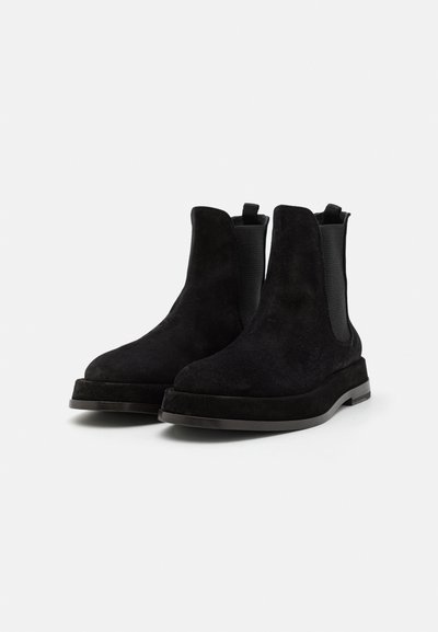 Botine Chelsea din suede negru, cu panouri laterale elastice texturate și bucle pentru tragere. Prezintă o talpă groasă din cauciuc negru. Finisaj neted.