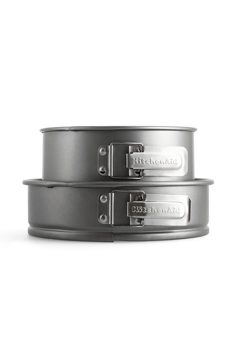 Twee ronde, grijze anti-aanbak springvormpannen met metalen sluitingen, met een gladde textuur en het "KitchenAid"-logo aan de zijkant.