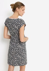 Μαύρο φόρεμα με κοντά μανίκια και αφηρημένο ροζ και μπεζ σχέδιο, με στρογγυλή λαιμόκοψη και ίσια γραμμή, που φτάνει μέχρι το μέσο του μηρού.