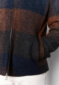 Men's zip-up jacket in wool blend, featuring horizontal stripes in dark blue, rust, and charcoal. Includes side pockets and a smooth zipper.