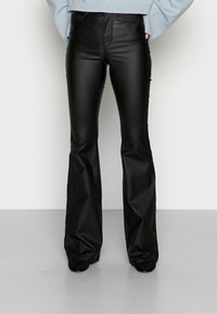 Pantalon évasé en similicuir noir à texture lisse, taille haute et poches avant, associé à un pull en maille bleu clair.