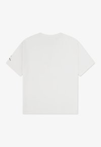 T-shirt di cotone bianco con maniche corte e scollatura tonda. Nessun motivo o grafica visibili. Presenta un piccolo accento nero sulla manica sinistra.