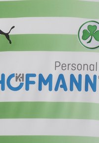 Grøn og hvidstribet sportstrøje med et sort puma-logo, et grønt kløveremblem og blå tekst der læser "Personal HOFMANN."