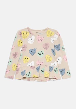 Beżowa bluzka z długim rękawem i peplum, ozdobiona kolorowymi twarzami postaci z kreskówek w pastelowych sercach, wykonana z miękkiego, elastycznego materiału.