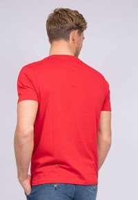 T-shirt rouge à manches courtes, en coton, à col rond, design ajusté, texture lisse, sans motifs ni graphiques visibles.