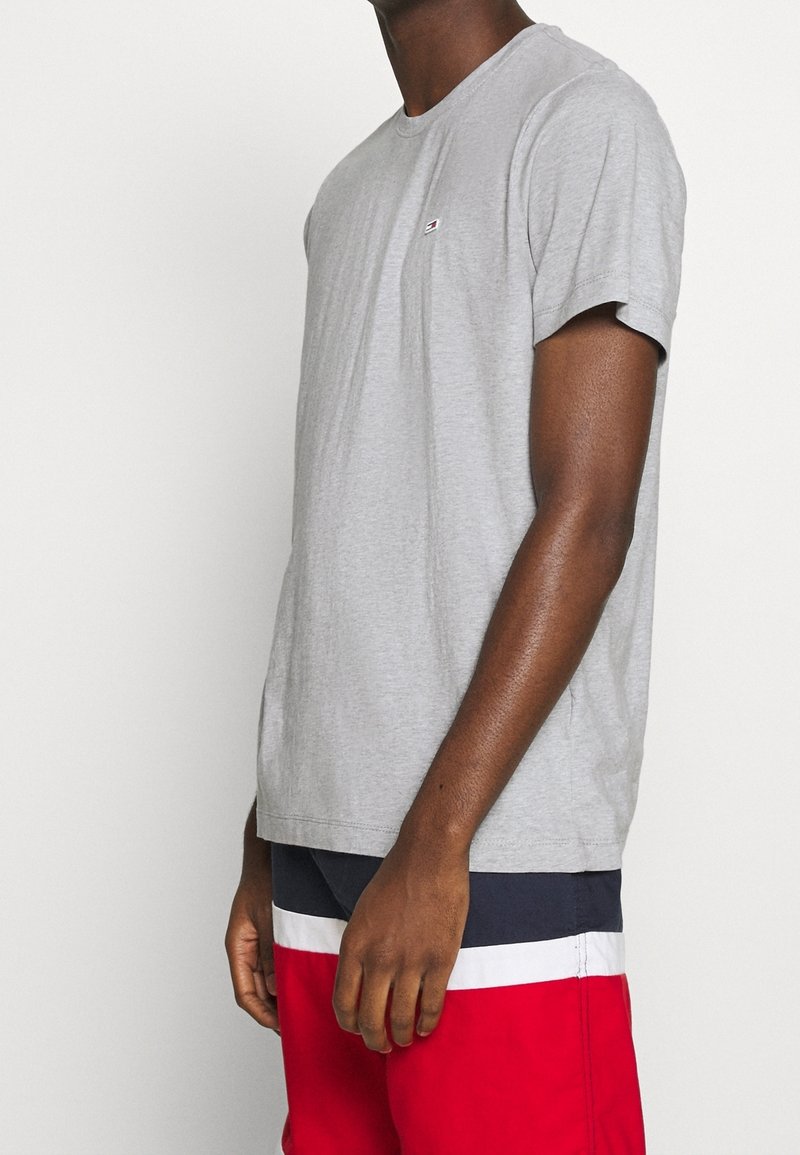 Šedé tričko s krátkým rukávem vyrobené z bavlny, s malým logem na levé straně hrudi, klasického střihu a jemnou texturou.