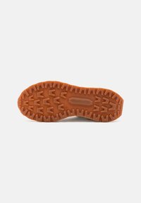 Gummisohle mit einem strukturierten, robusten Muster. Orange Farbe mit tiefen Profilen für besten Halt. Flache, runde Form, die für Stabilität sorgt.