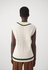 Pull sans manches tricoté en crème avec un motif en torsades, présentant un col côtelé multicolore et des rayures vertes à l'ourlet.