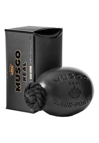 Schwarze Rasierseife in runder Form, mit einem geflochtenen Griff, geprägt mit "MUSGO REAL" und "GLAUS-PORTO". Verpackung in schwarzer Box.