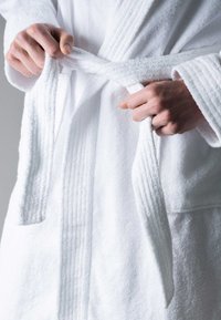 White terry cloth bathrobe with a textured finish. Tied at the waist, features a shawl collar and two side pockets.