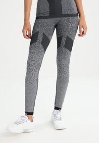 Leggings sportivi in tessuto grigio screziato con dettagli in rete nera. Design aderente con una texture liscia e dettagli in contrasto sulla vita.
