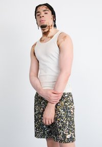White ribbed tank top and dark floral-patterned shorts with yellow and pink accents. Shorts feature a drawstring and are branded with a logo.