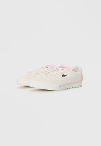 Lacoste tenisice u svijetlosmeđem antilopu s ružičastim vezicama, retro dizajn, okrugli vrh i bijela gumena potplat s teksturiranim uzorkom.