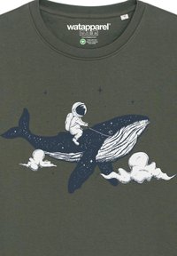 Olivegrünes T-Shirt mit einem weißen Druckmotiv eines Wals und eines Astronauten, der auf ihm reitet, umgeben von Wolken und Sternen.