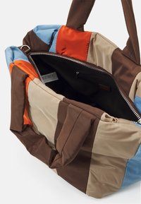 Sac fourre-tout rembourré avec un design en patchwork aux couleurs marron, beige, orange et bleu. Dispose d'une fermeture éclair et d'une poche intérieure.
