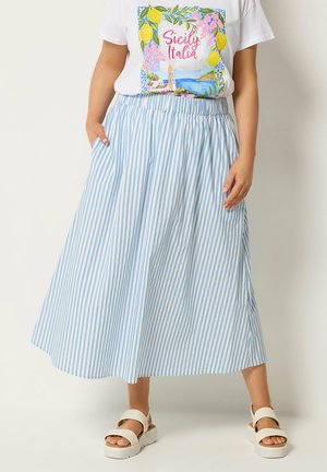 Kvinde iført hvide sandaler, blå og hvide vertikalt striped midi nederdel og hvid T-shirt med farverigt Sicily Italia tryk.