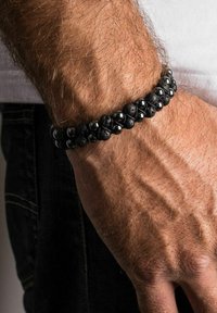 Black bead bracelet made of volcanic rock and polished hematite, featuring a textured design with varying sizes of round beads.