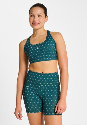 Sportstøjssæt i blågrøn bestående af en sports-BH og matchende shorts med et gentaget lille mønster. Materialet virker strækbart med en glat tekstur.