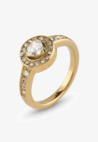 Anillo de metal dorado con una piedra central en forma de pera rodeada de piedras más pequeñas y transparentes, con "GUESS" grabado en la banda.