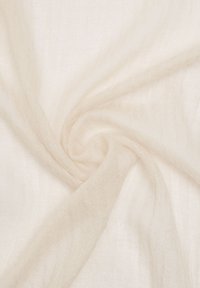 Przezroczysta, kremowa tkanina o miękkiej, delikatnej fakturze, ukazująca subtelne zmiany w świetle, wydaje się zwisać w płynnych fałdach.