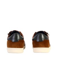 Sneaker in suede marrone con accenti in pelle blu navy, suola in gomma bianca e una texture liscia. Presenta occhielli e un dettaglio di cucitura sul retro.