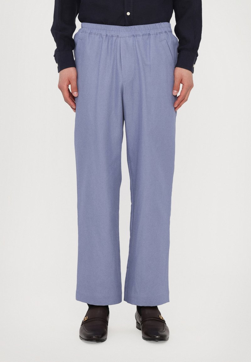 Helle blaue Hose mit elastischem Bund, einem entspannten Schnitt und geraden Beinen. Der Stoff wirkt weich, glatt und leicht.